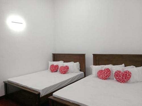 - 2 lits avec des oreillers rouges et des coeurs dans l'établissement Idom Cozy, à Gampola