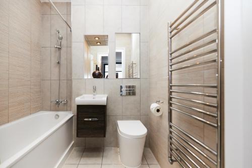 a bathroom with a toilet and a sink and a tub at The Wembley Escape - Lovely 2BDR Flat in London
