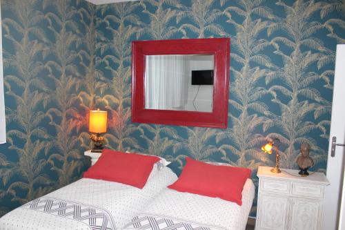 una camera da letto con specchio e letto con cuscini rossi di PARIS de FLORE Stane a Malakoff