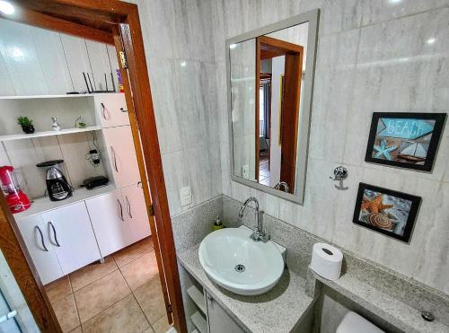 a bathroom with a sink and a mirror at Casa charmosa pé na areia por do sol in Florianópolis