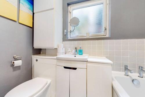 a bathroom with a sink and a toilet and a window at Stunning 2BDR with beautiful garden in London