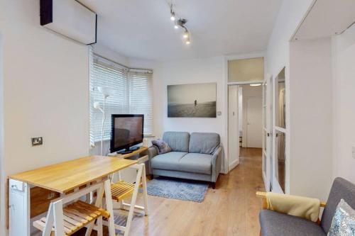 a living room with a table and a couch and a television at Stunning 2BDR with beautiful garden in London