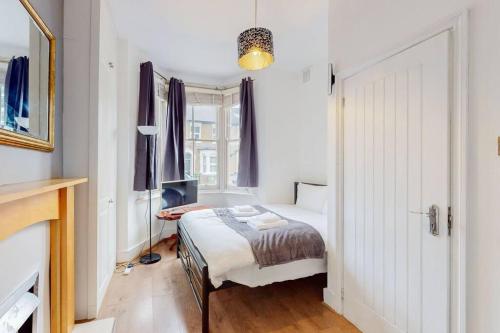 Habitación blanca con cama y ventana en Stunning 2BDR with beautiful garden en Londres