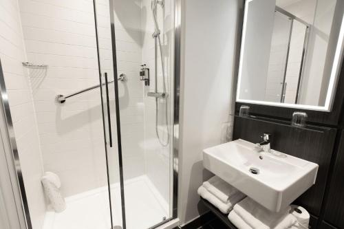 a white bathroom with a sink and a shower at The Address Glasgow in Glasgow