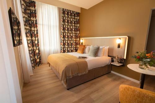 a hotel room with a large bed and a table at The Address Glasgow in Glasgow