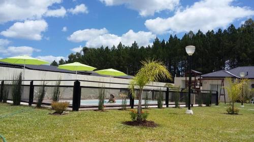 ein Pool mit grünen Sonnenschirmen im Hof in der Unterkunft Complejo Rincon del Uruguai in Colón