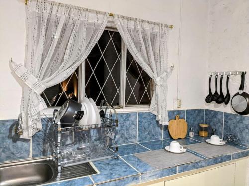 una cocina con fregadero y una ventana con cortinas en Hermosa casita en centro de Cuenca, en Cuenca