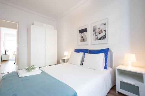 een slaapkamer met een wit bed en een blauwe deken bij BmyGuest - Boa Hora Apartment in Lissabon
