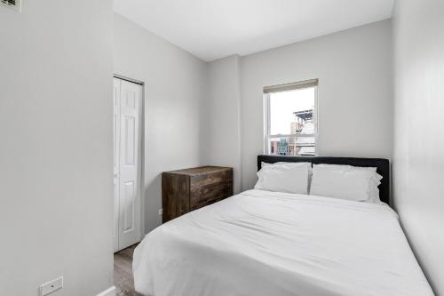 um quarto branco com uma cama e uma janela em Spacious Hideaway minutes from Downtown with Parking em Chicago