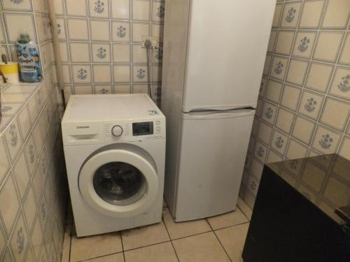 a small kitchen with a washing machine and a refrigerator at Many Worlds Meet - EuroStar, Wimbledon 30 mins, Central London, Gatwick 15 mins - Spacious, Sleeps up to 16 plus Cot - Free WiFi, Parking - Next to Lloyd Park, Great for Families, Walkers, Relocators - Ideal for Contractors in Croydon