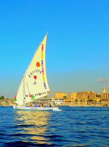 a sailboat on the water with a city in the background at Felucca SUNSHINE in Luxor