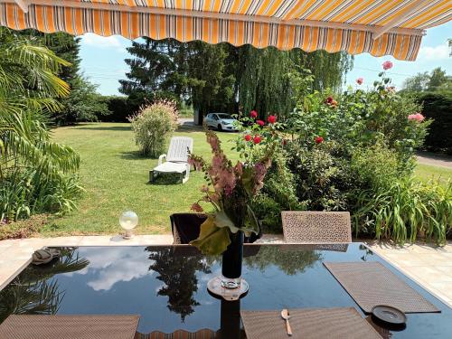 un jarrón de flores en una mesa junto a una piscina en 2 Chambres chez l habitant, en Parigné-lʼÉvêque