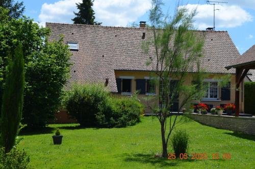 una casa con un patio verde con un árbol en 2 Chambres chez l habitant, en Parigné-lʼÉvêque