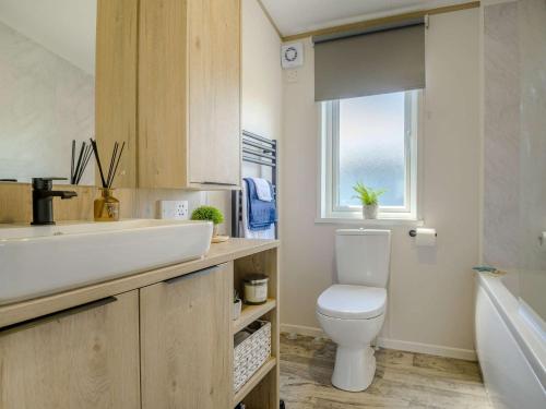 a bathroom with a sink and a toilet and a window at 3 Bed in Brean 88890 in Berrow