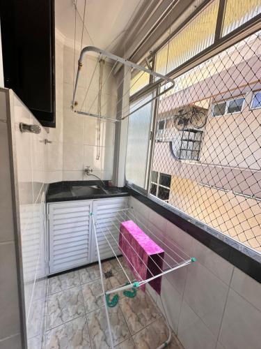uma pequena cozinha com um lavatório e uma janela em Apartamento Temporada Guarujá no Guarujá