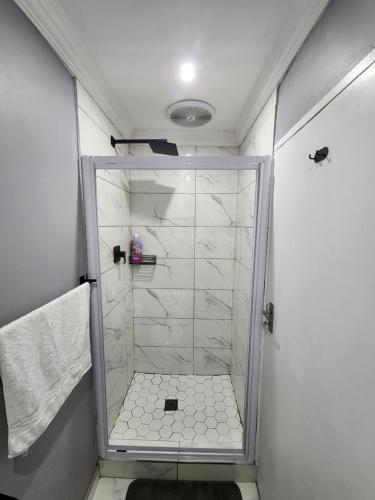La salle de bains est pourvue d'une douche avec une porte en verre. dans l'établissement Vusi's Guesthouse, à Durban