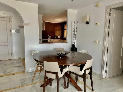 una sala da pranzo con un tavolo di legno e sedie bianche di Magna Marbella Golf Resort Apartment a Marbella