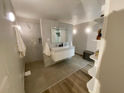 een witte badkamer met een wastafel en een spiegel bij Myrtus - House with sea view and garden in Funchal
