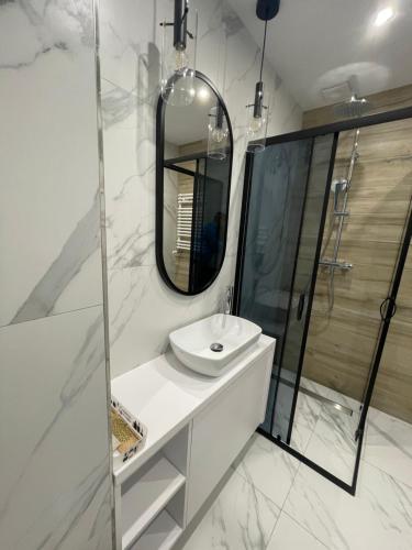 Baño blanco con lavabo y espejo en Rainbow Apartments Premium CENTRUM, en Kielce