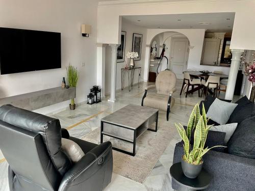 un soggiorno con un divano e una TV a parete di Magna Marbella Golf Resort Apartment a Marbella