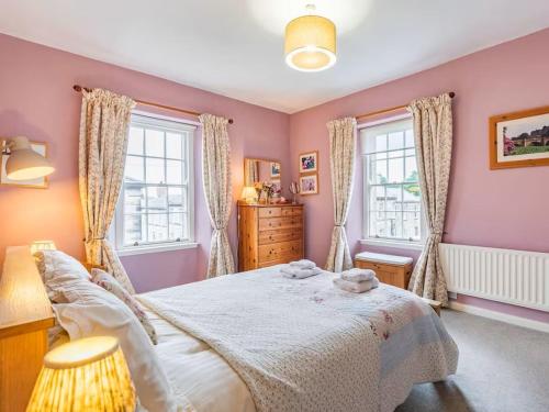 ein Schlafzimmer mit einem großen Bett und zwei Fenstern in der Unterkunft Peaseblossom House, a charming Grade II Listed Building, in a great location in Alnwick in Alnwick