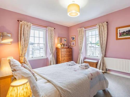 a bedroom with a large bed and two windows at Peaseblossom House, a charming Grade II Listed Building, in a great location in Alnwick in Alnwick