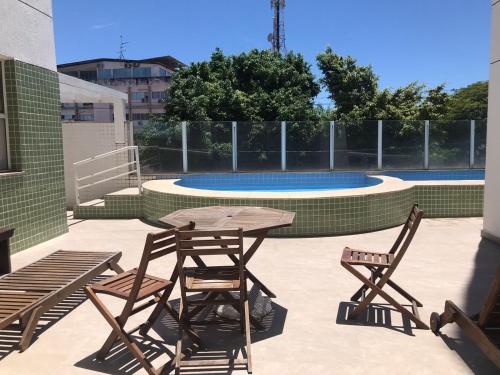 eine Terrasse mit einem Tisch, 2 Stühlen und einem Pool in der Unterkunft Cabo Frio com piscina e excelente localização in Cabo Frio