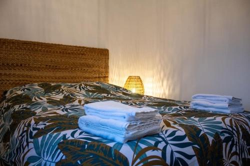 three towels stacked on top of a bed with a lamp at Le Fontaine - Hyper Centre - Vue Cathédrale - Wifi in Mende