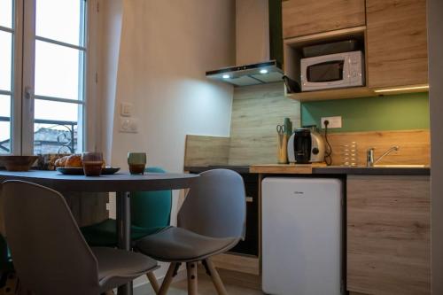 eine Küche mit einem Tisch, Stühlen und einer Mikrowelle in der Unterkunft Le Fontaine - Hyper Centre - Vue Cathédrale - Wifi in Mende