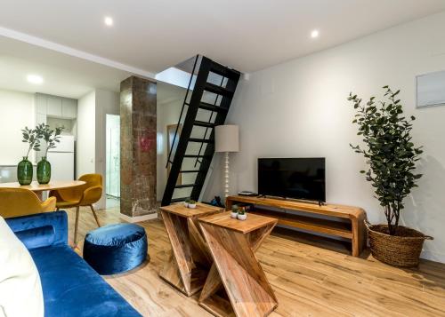 a living room with a blue couch and a tv at Stylish Dúplex - 1 Bd 1Bth- Plaza Castilla in Madrid