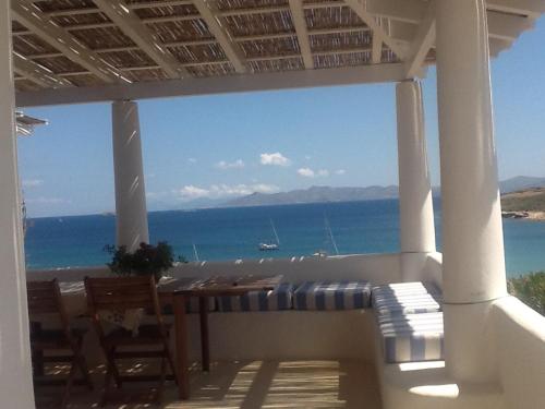 - une terrasse couverte avec une table et des chaises et l'océan dans l'établissement casa koklakura, à Lipsi