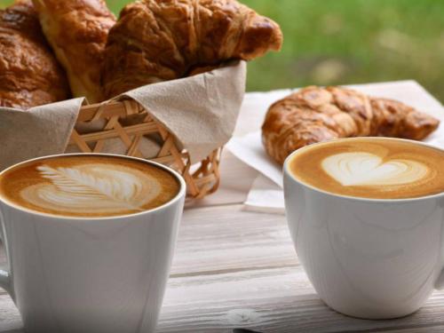 zwei Tassen Kaffee und ein Korb mit Croissants in der Unterkunft Sun shine in Cesano Boscone