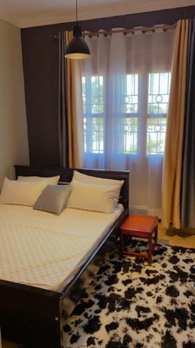een slaapkamer met een groot bed en een raam bij Kamel Furnished Apartments! in Wakiso