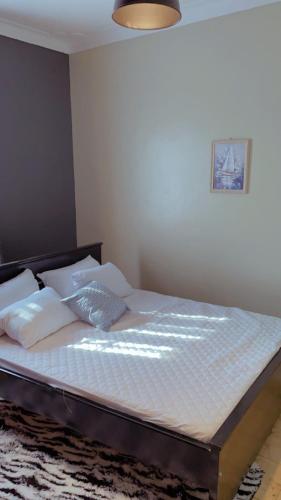 een bed met witte lakens en kussens in een slaapkamer bij Kamel Furnished Apartments! in Wakiso