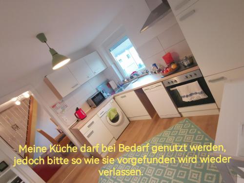 una cucina con armadietti bianchi e pavimenti in legno di Privatzimmer in ruhiger Lage in Heidenheim/ Steinheim am Albuch a Steinheim am Albuch
