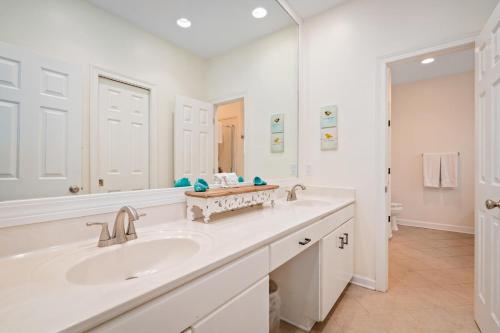 a white bathroom with a sink and a mirror at 025 The Sanderling in Dauphin Island