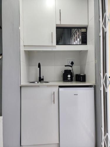ダーバンにあるVusi's Guesthouseの白いキッチン(白いキャビネット、シンク付)