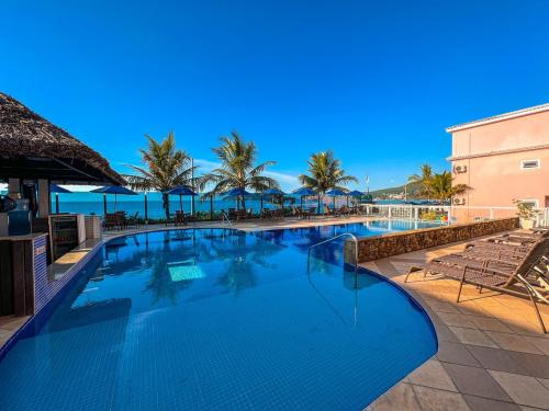 a swimming pool at a resort with palm trees and the ocean at Pousada Vila do Coral in Bombinhas