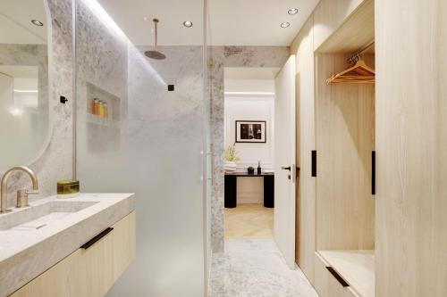 bagno con doccia, lavandino e bancone di TheLander - Champs Elysées Serviced Apartments a Parigi
