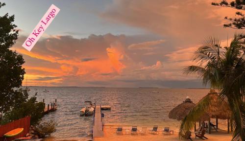 a beach with a dock and the ocean at sunset at Sunset Cove Beach Resort in Key Largo