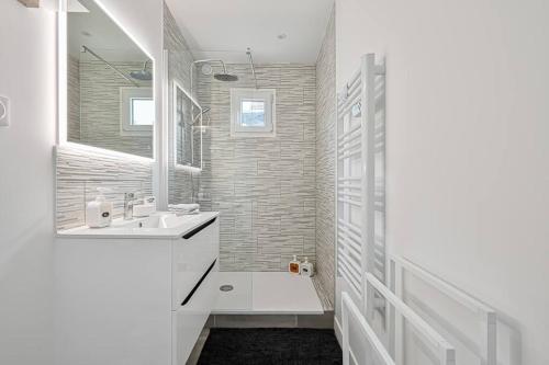 a white bathroom with a sink and a mirror at La parenthèse in Claye-Souilly