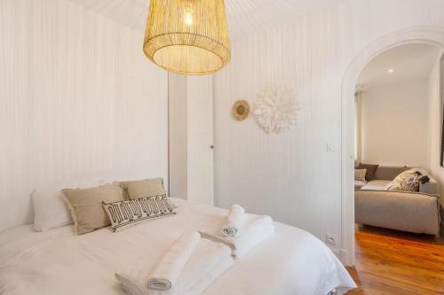 a bedroom with a white bed with a chandelier at Appartement rue Gambetta, plage à 2 min in Saint-Jean-de-Luz