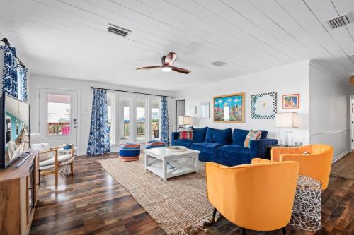 a living room with a blue couch and orange chairs at 017 The Sand House in Dauphin Island