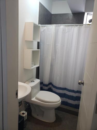 a bathroom with a white toilet and a sink at Playa el Silencio lindo apartamento! no mascotas deposito para reservar in Bombiso
