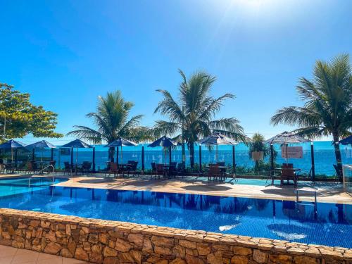 una piscina con palmeras y sombrillas azules en Pousada Vila do Coral, en Bombinhas