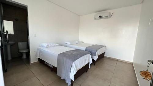 ein Hotelzimmer mit 2 Betten und einem Bad in der Unterkunft Pousada Ipê Amarelo in Divisa