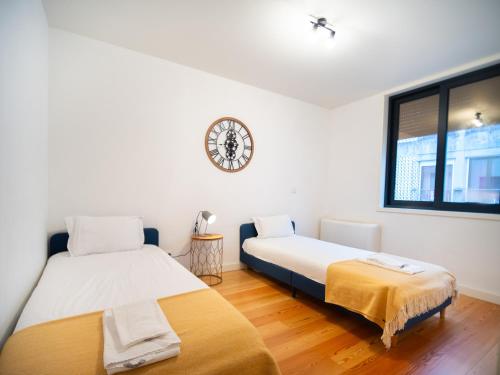 2 Betten in einem Zimmer mit einer Uhr an der Wand in der Unterkunft Oporto City View - Alves da Veiga in Porto