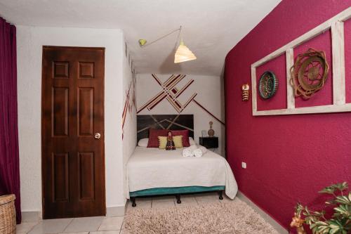 1 dormitorio con cama y pared de color rosa en Casa Amaranto, en Panajachel