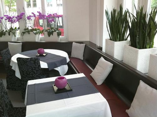 فندق هوتينغن في زيورخ: مطعم به طاولتين ونباتات خزف