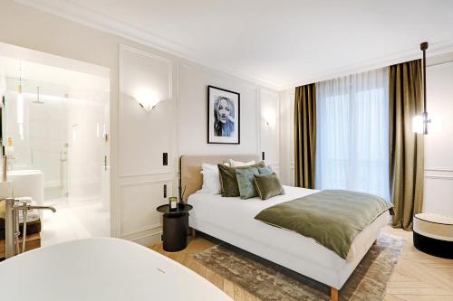 una camera bianca con letto e bagno di TheLander - Champs Elysées Serviced Apartments a Parigi
